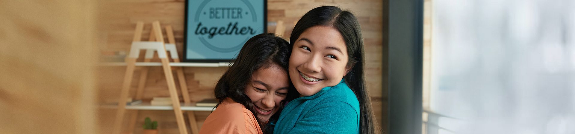  two high school girls hugging while staring at the camera with content facial expressions 